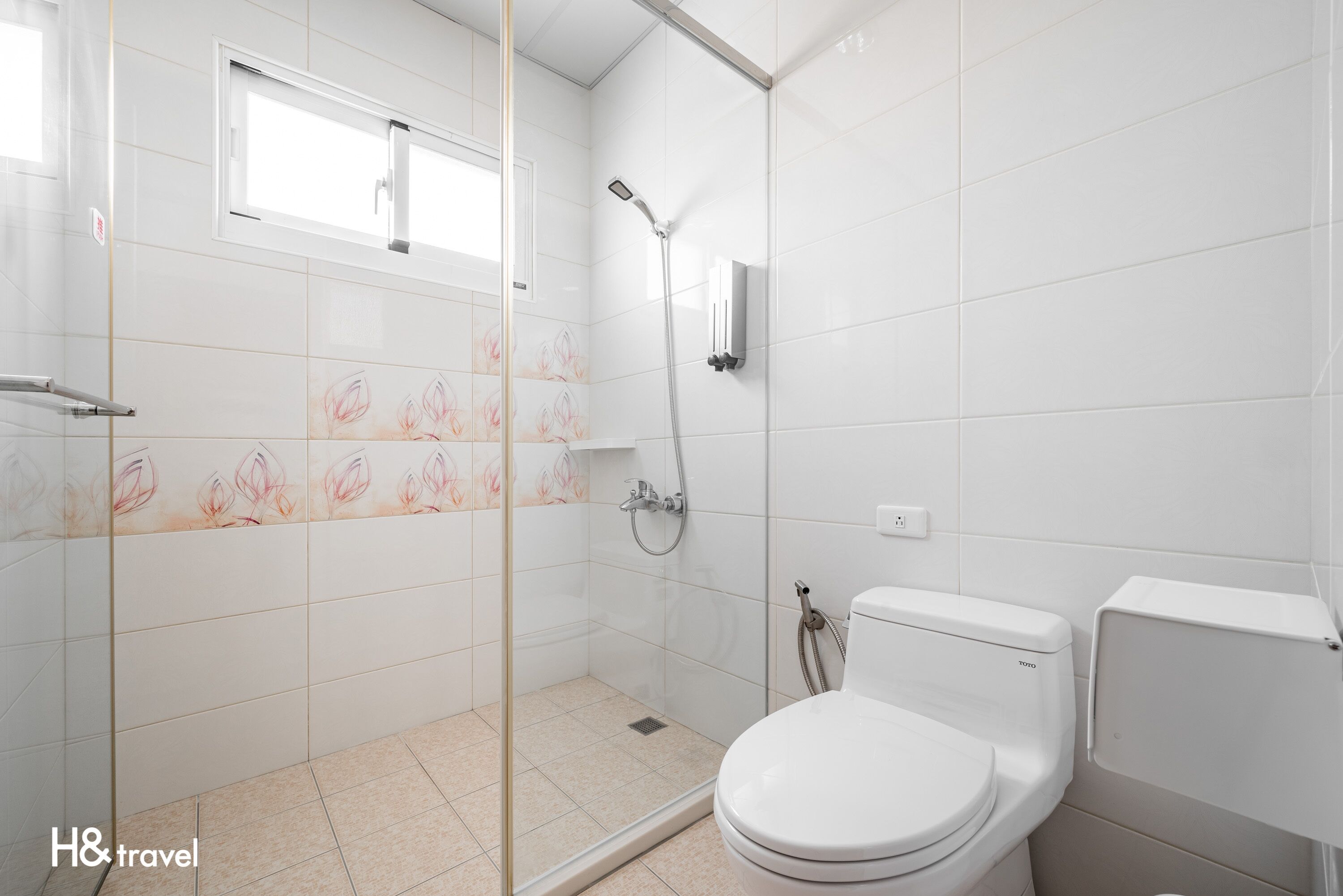 A modern bathroom with a glass-enclosed shower, a toilet, and a window.