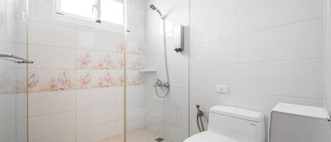 A modern bathroom with a glass-enclosed shower, a toilet, and a window.