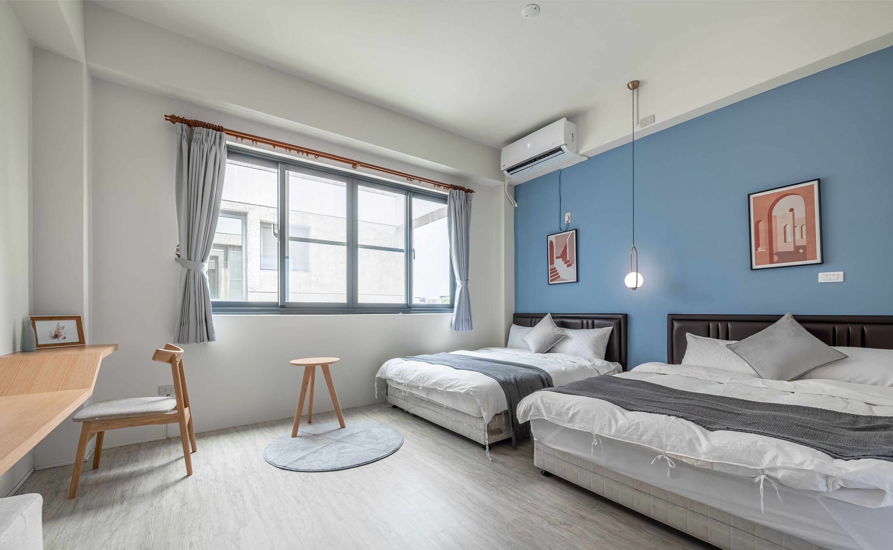 Un dormitorio moderno con dos camas, un escritorio y una ventana con cortinas.