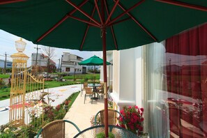 Un patio con mobiliario exterior, una jaula decorativa y vista a la calle.