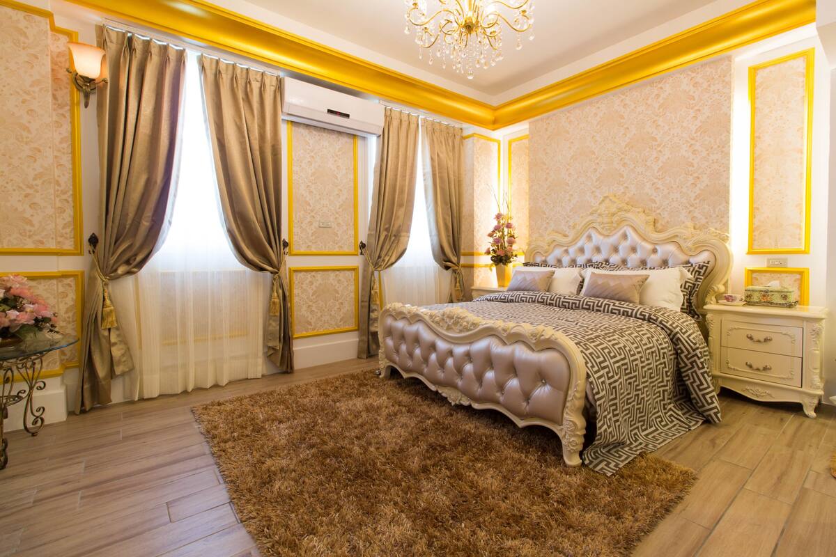 Quarto com uma cama grande, mesa de cabeceira, cômoda e lustre.