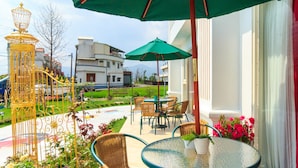 An outdoor seating area with wicker chairs and a round table, green umbrellas, and potted plants. - Alice Wonderland B&B (Dongshan)