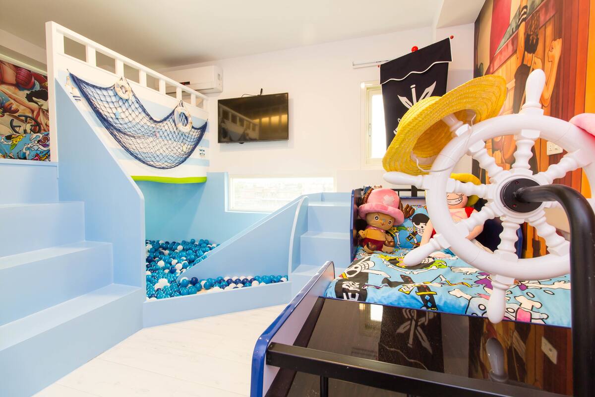 Uma área de recreação infantil com escorrega, piscina de bolinhas e um volante de brinquedo.