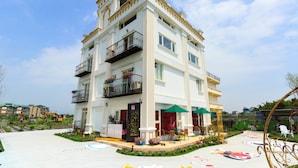 A multi-story hotel with balconies, outdoor seating, and a garden area. - Alice Wonderland B&B (Dongshan)
