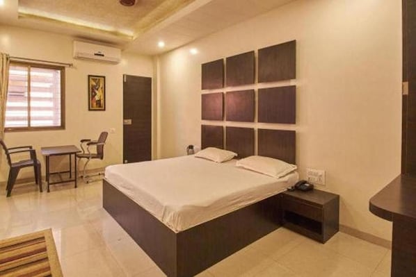 A bedroom with a large bed, bedside tables, a desk, and chairs.
