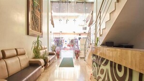 Um saguão de hotel com balcão de recepção, um sofá e uma escada.