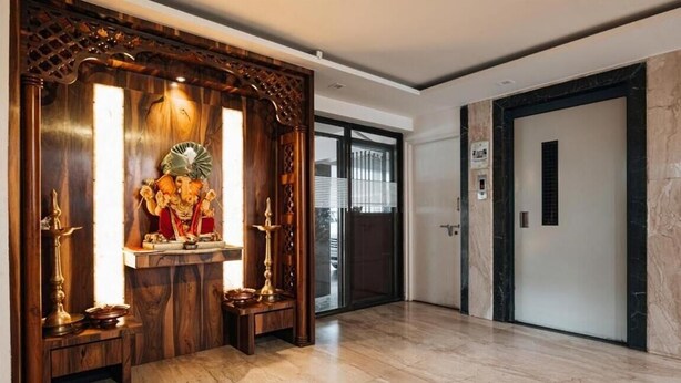 Uma área de recepção com um santuário de madeira, piso de mármore e um elevador moderno.