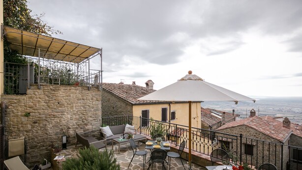 A stone patio with outdoor seating, a covered area, and a view of the sea.