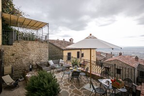 A stone patio with outdoor seating, a covered area, and a view of the sea. - 3BR-3BA apt, walk to downtown Cortona, with airco, wifi and amazing view (Cortona)