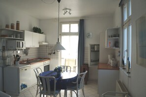 Une cuisine de taille réduite avec des meubles blancs, un four à micro-ondes, un évier et une table à manger avec des chaises.