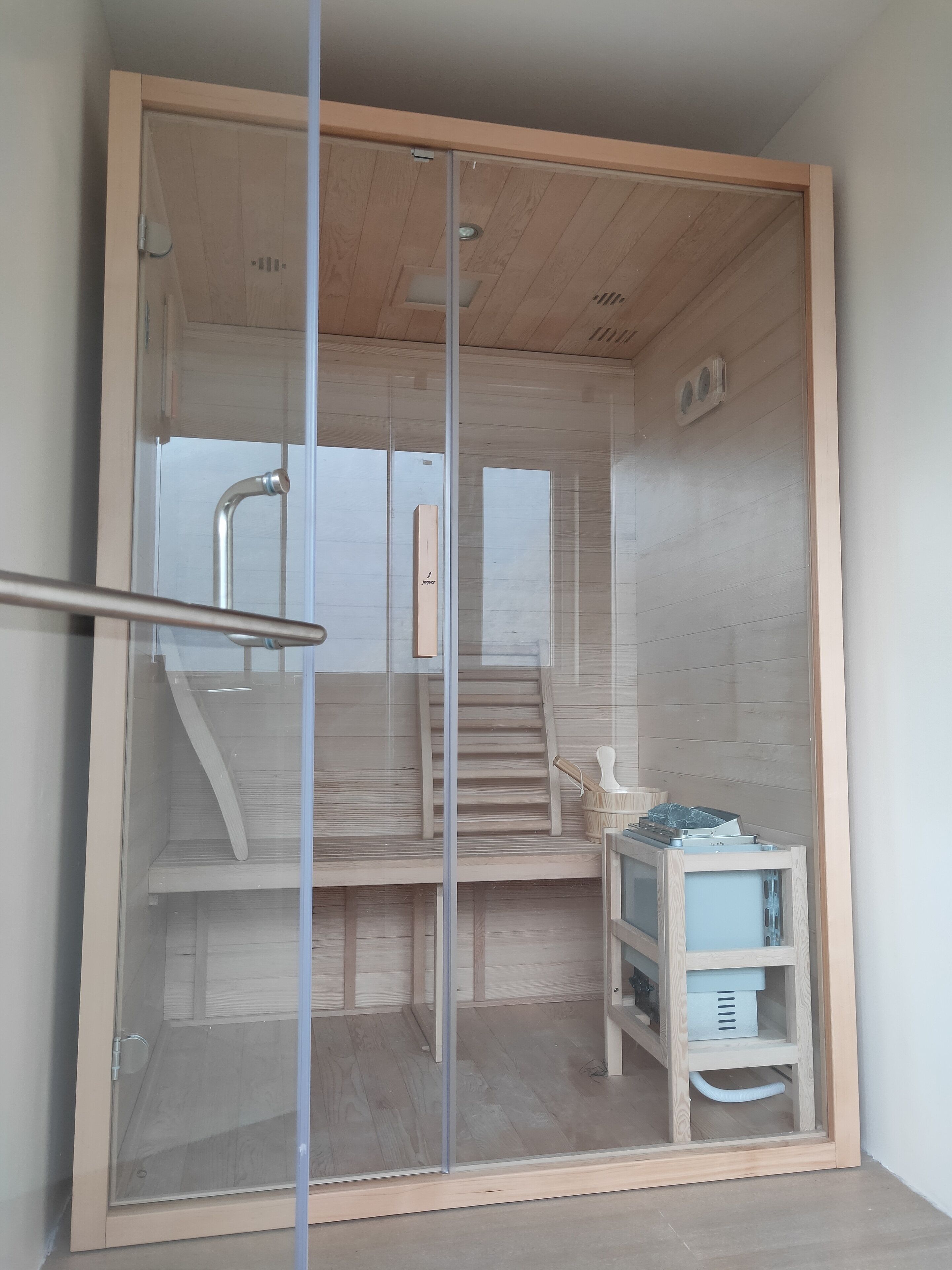 A glass-enclosed shower area with wooden steps and a small table with a towel.