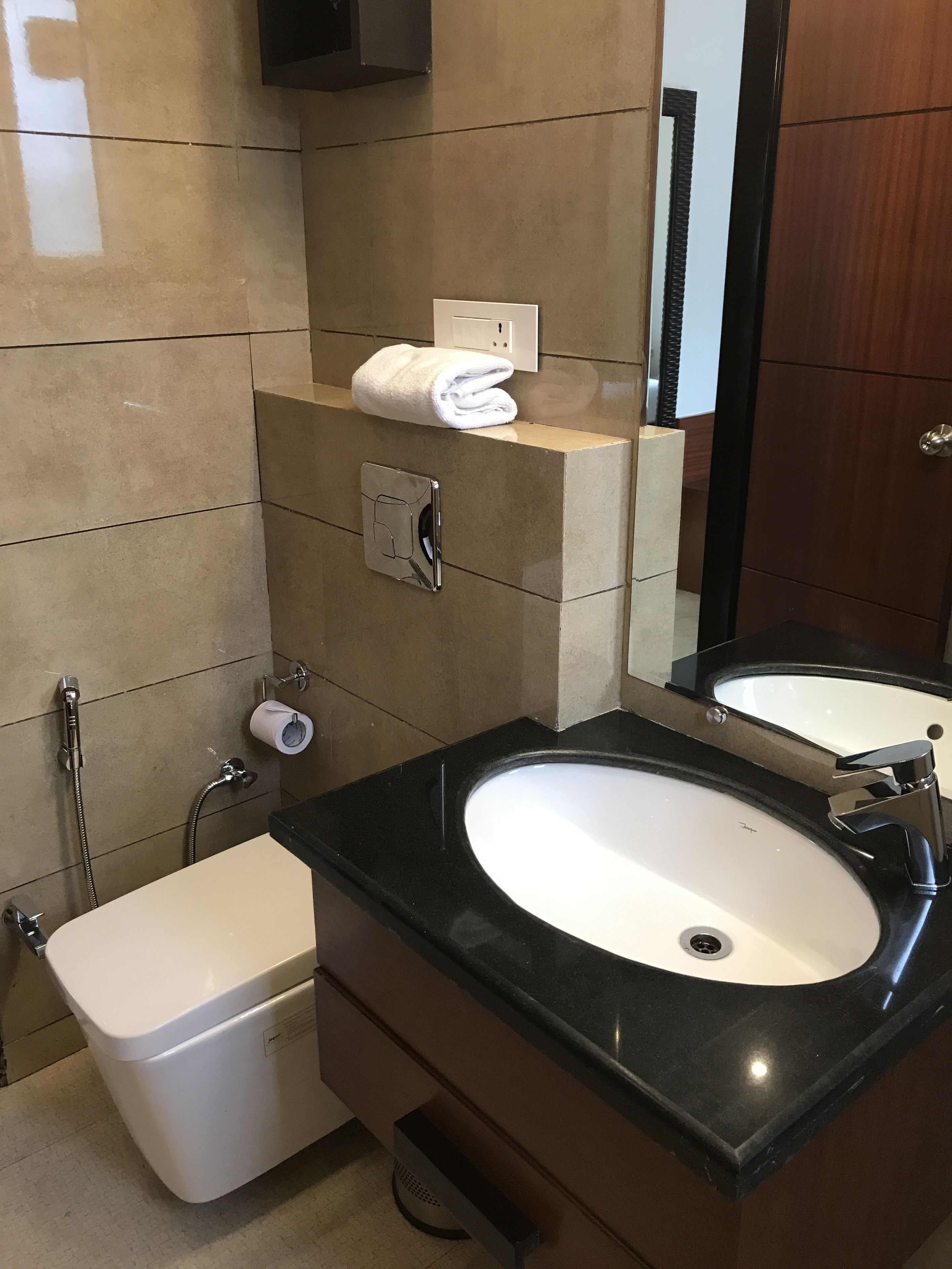 A modern bathroom with a black countertop sink, a white toilet, and a towel rack.
