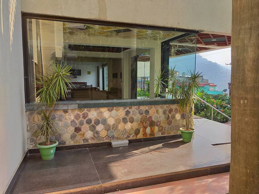 A modern building with a stone-tiled exterior, large windows, and potted plants.