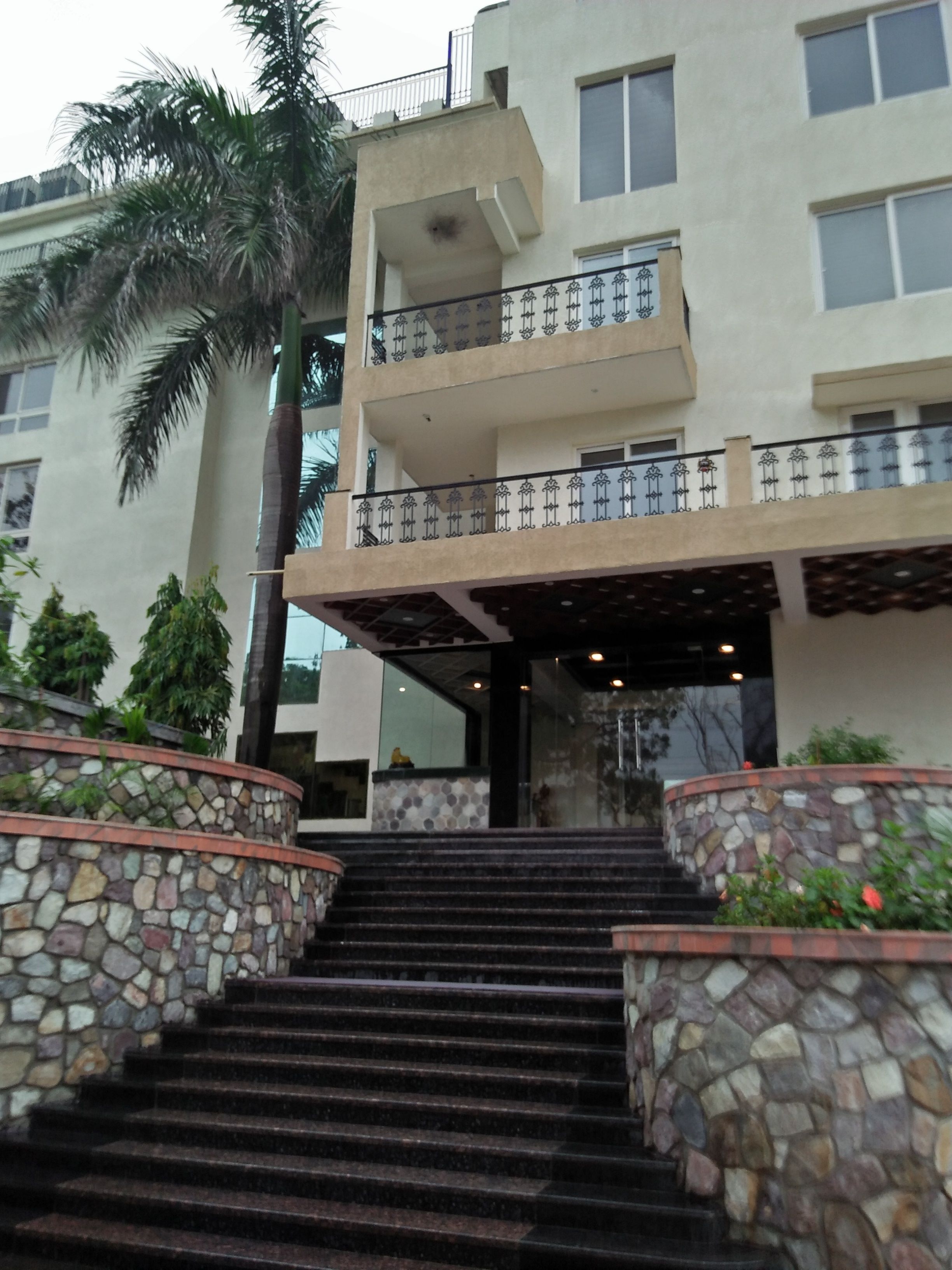 Un edificio de varios pisos con una escalera de piedra que conduce a un acceso cubierto.