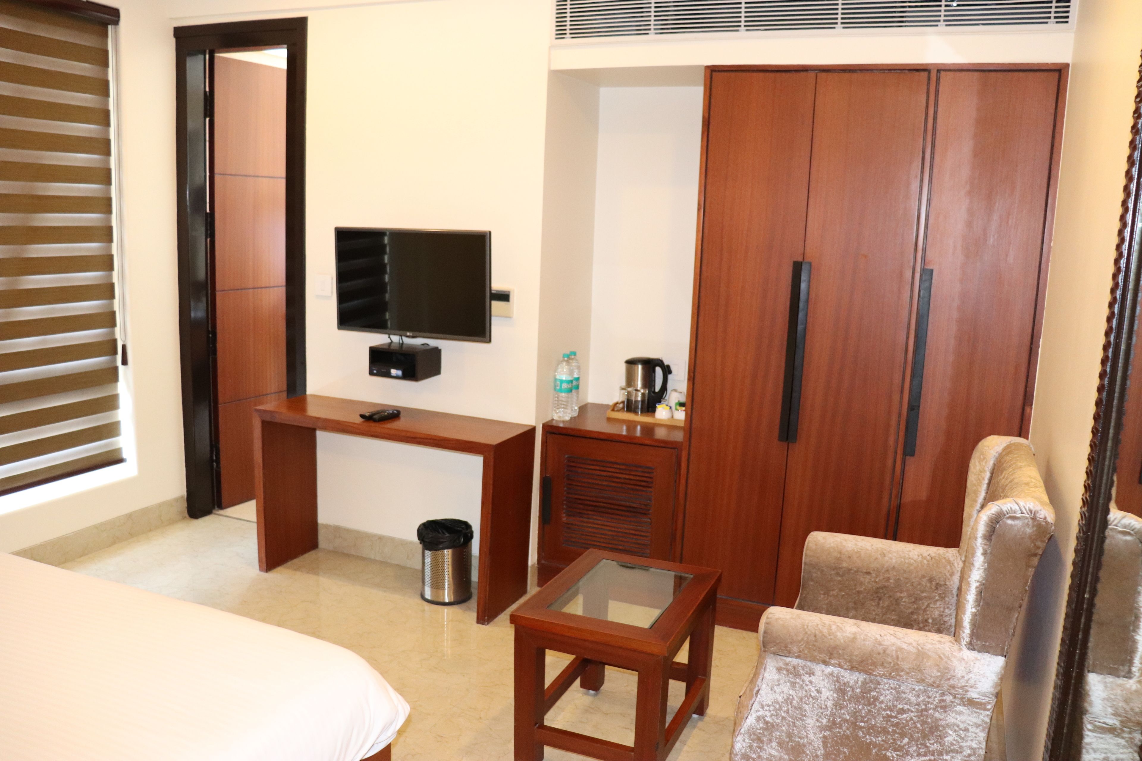 Une chambre d’hôtel comprenant un lit, un bureau avec une télévision, une armoire et une chaise.