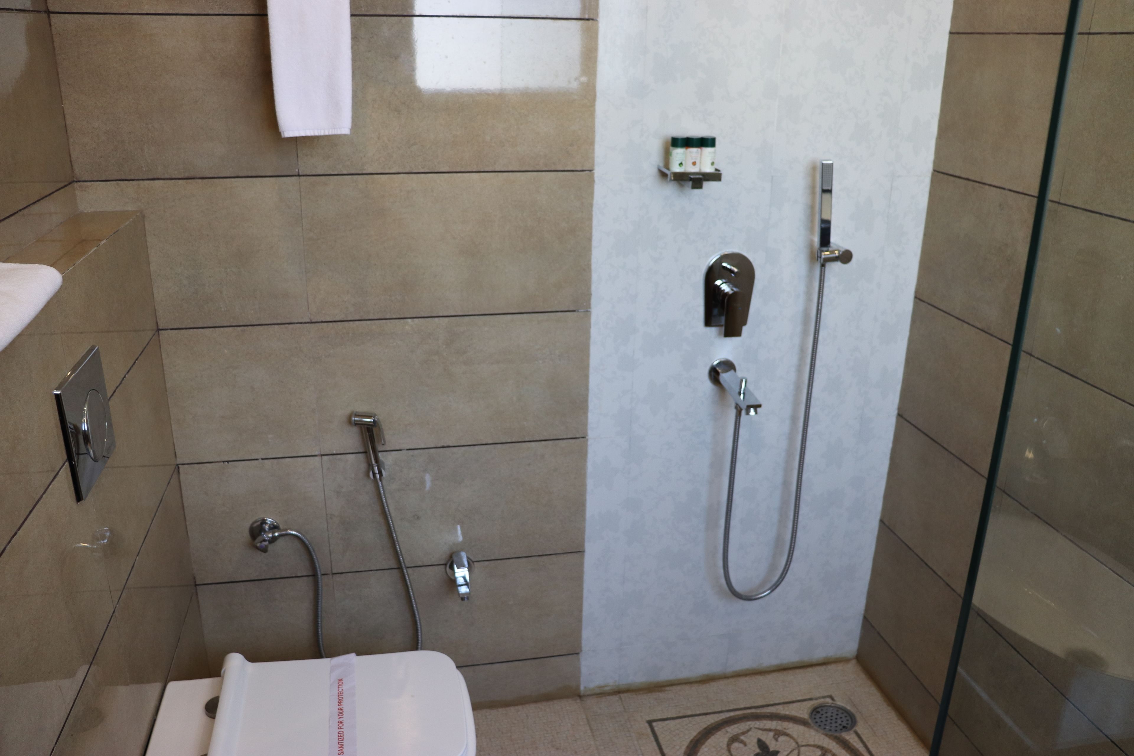 Un baño moderno con inodoro, ducha y zona de ducha con mampara de vidrio.