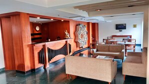Un hall con mostrador de recepción, zona de estar y televisor.