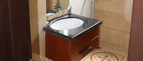 A bathroom with a glass-enclosed shower, a sink, and a toilet.