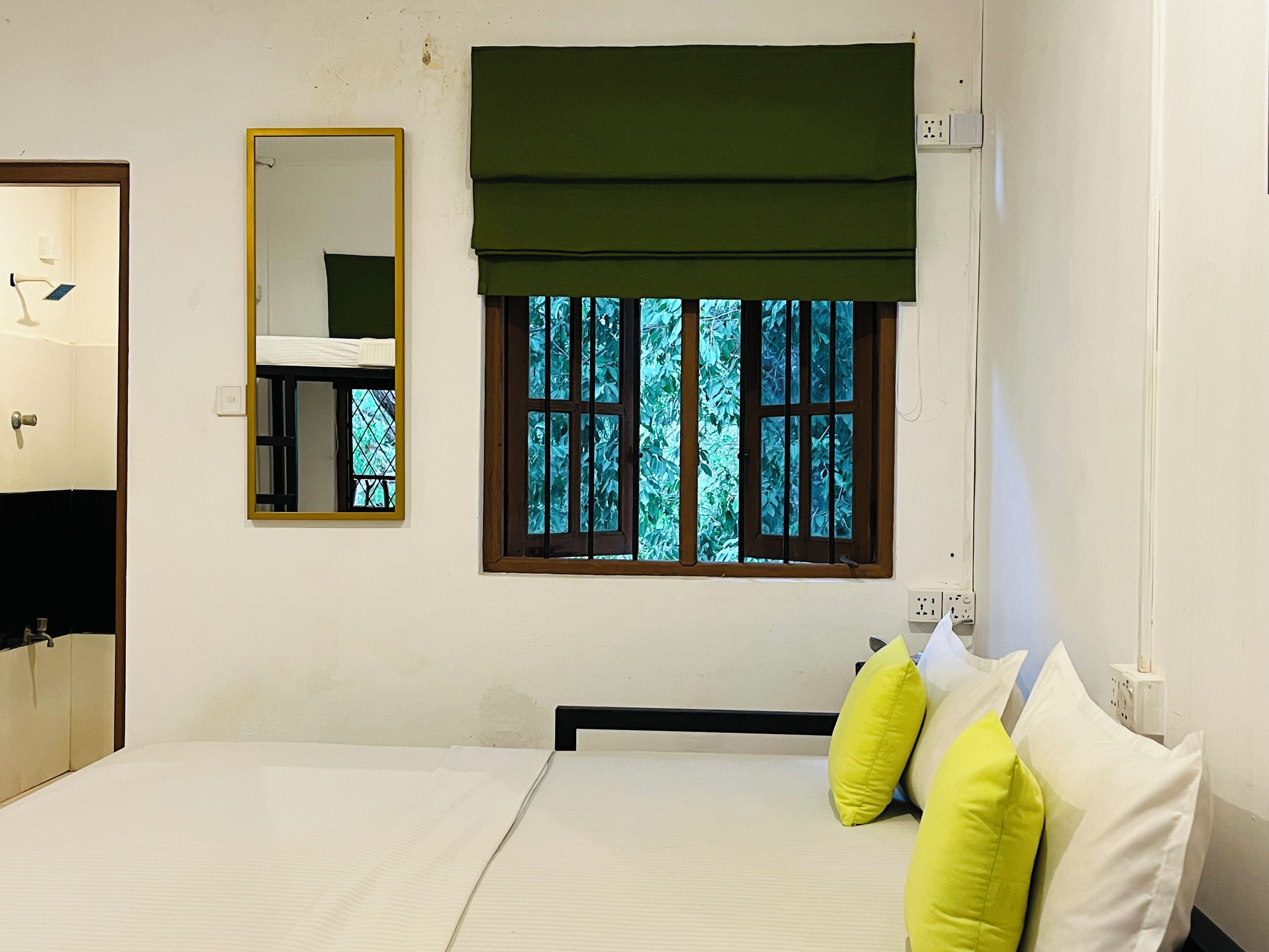 Une chambre à coucher avec un lit, une fenêtre donnant sur des arbres, un miroir et une table de chevet.