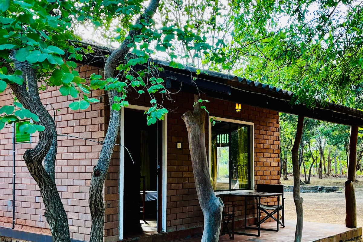 Uma cabana rústica com fachada de tijolos, janelas grandes e um alpendre coberto.