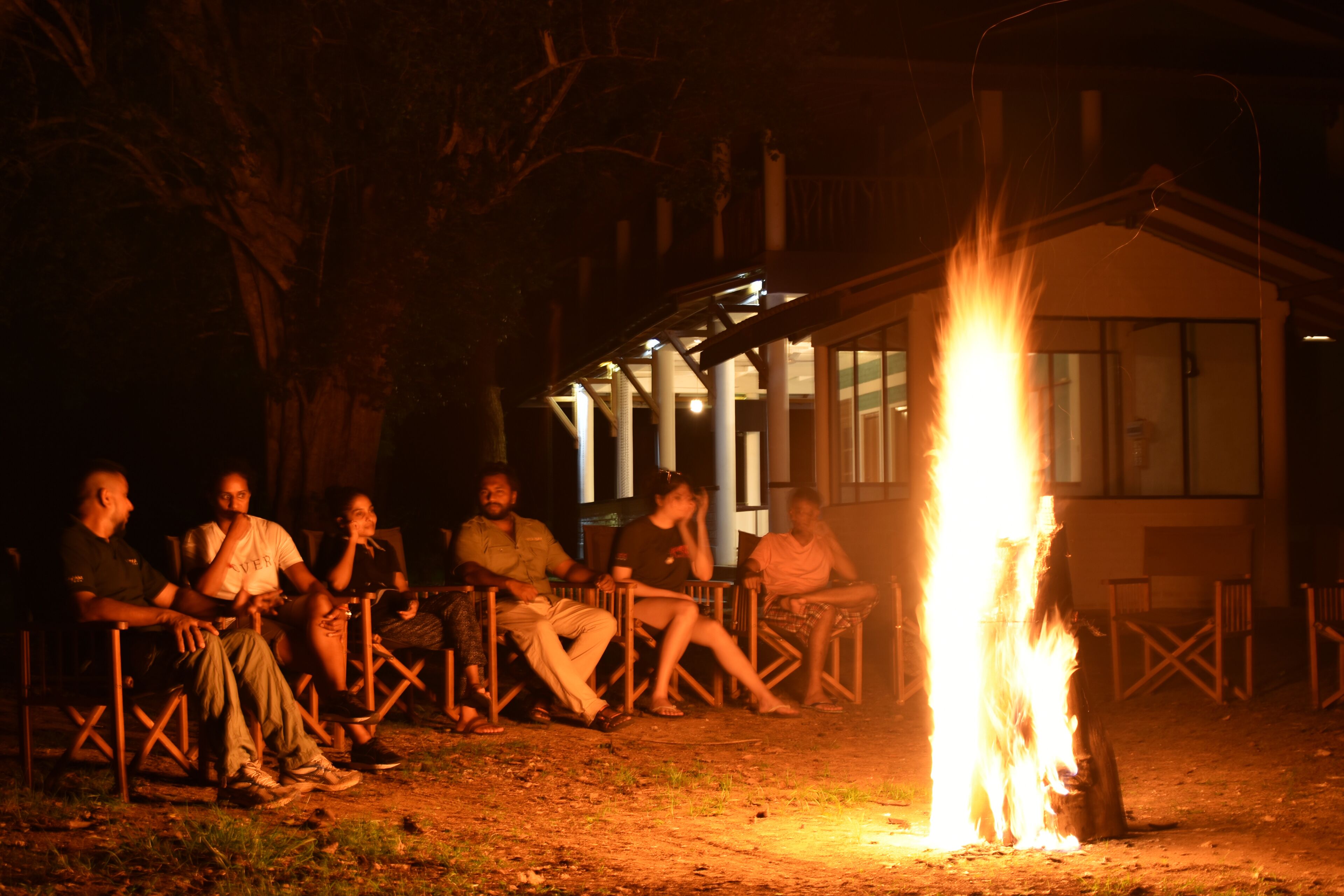 A group of people seated around a campfire at night.