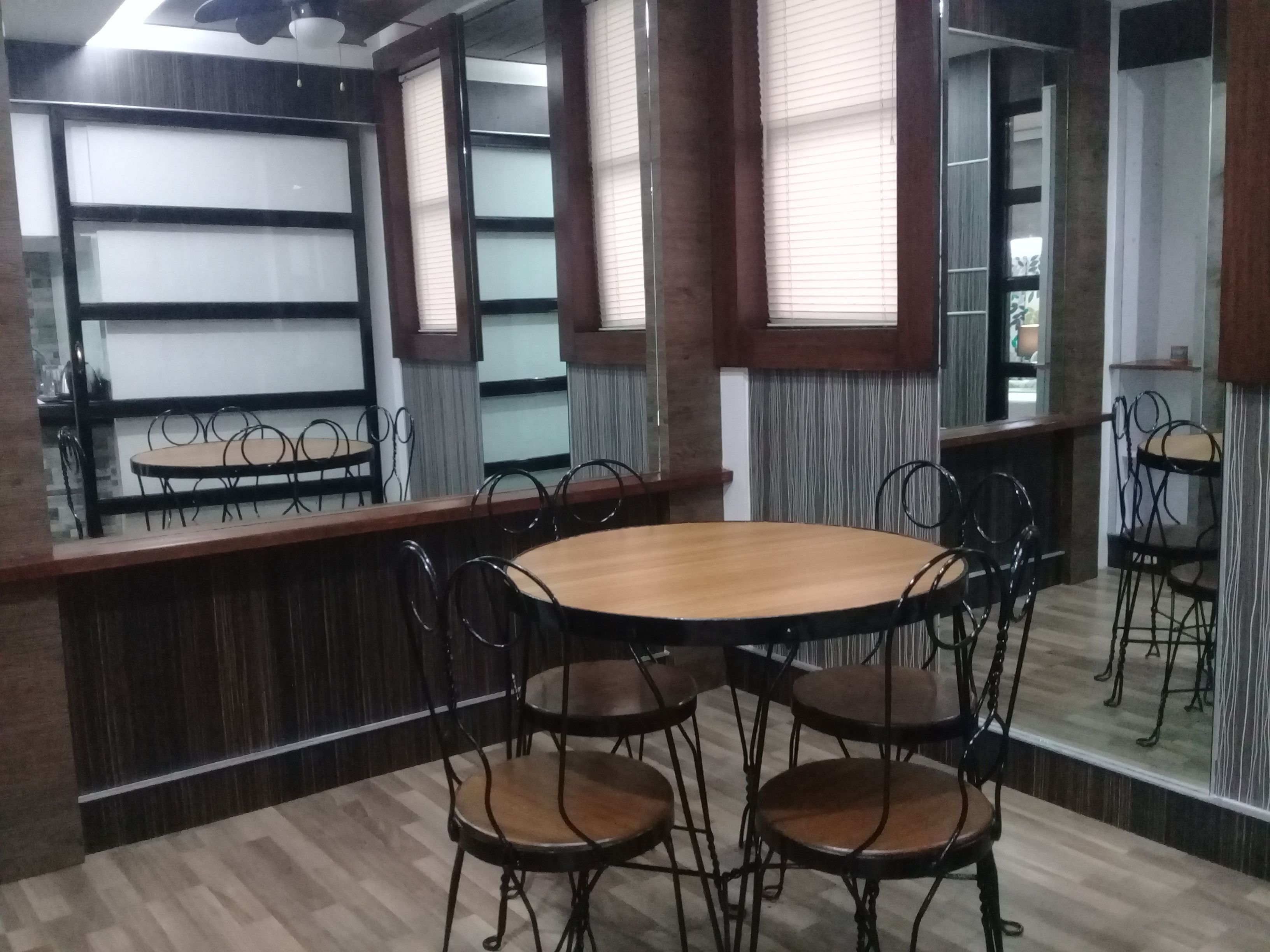 Une salle de conférence dotée d’une table ronde et de six chaises, d’un plancher en bois et d’une cloison en bois avec des panneaux de verre.