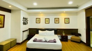 A modern bedroom with a large bed, wooden flooring, and framed pictures on the walls. - Casa Verde Hotel & Events Center (Imus)