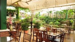 An indoor garden with wooden tables and chairs, surrounded by various plants and a bamboo fence. - Casa Verde Hotel & Events Center (Imus)