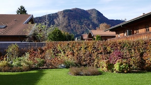 A residential area with a mountain in the background, a well-maintained garden, and houses with red-tiled roofs. - Bodenschneid Suite Garden View West - Bodenschneid Suites Rottach-Egern (Rottach-Egern)