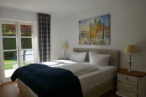 Une chambre à coucher avec un lit, deux tables de chevet, une fenêtre avec des rideaux et un tableau au mur.