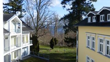 Ein zweistöckiges Gebäude mit einem Balkon im oberen Geschoss, einem gepflegten Rasen und einem großen Baum im Hintergrund.