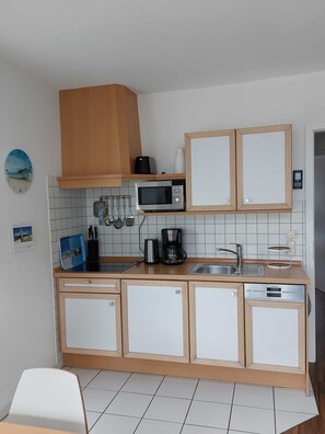 A compact kitchen with a microwave, coffee maker, and a Siemens dishwasher.