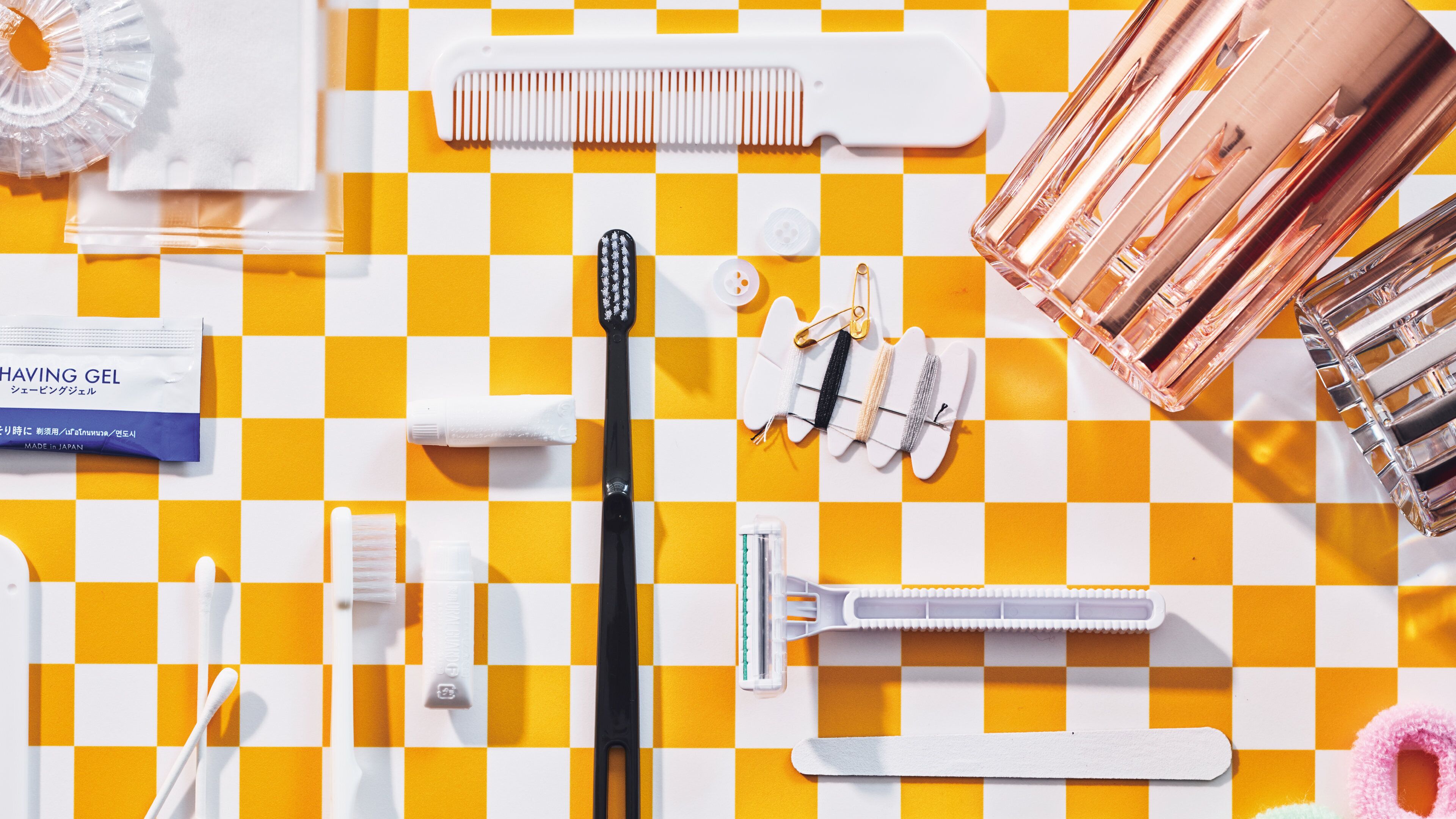 A variety of personal care items arranged on a checkered tablecloth.