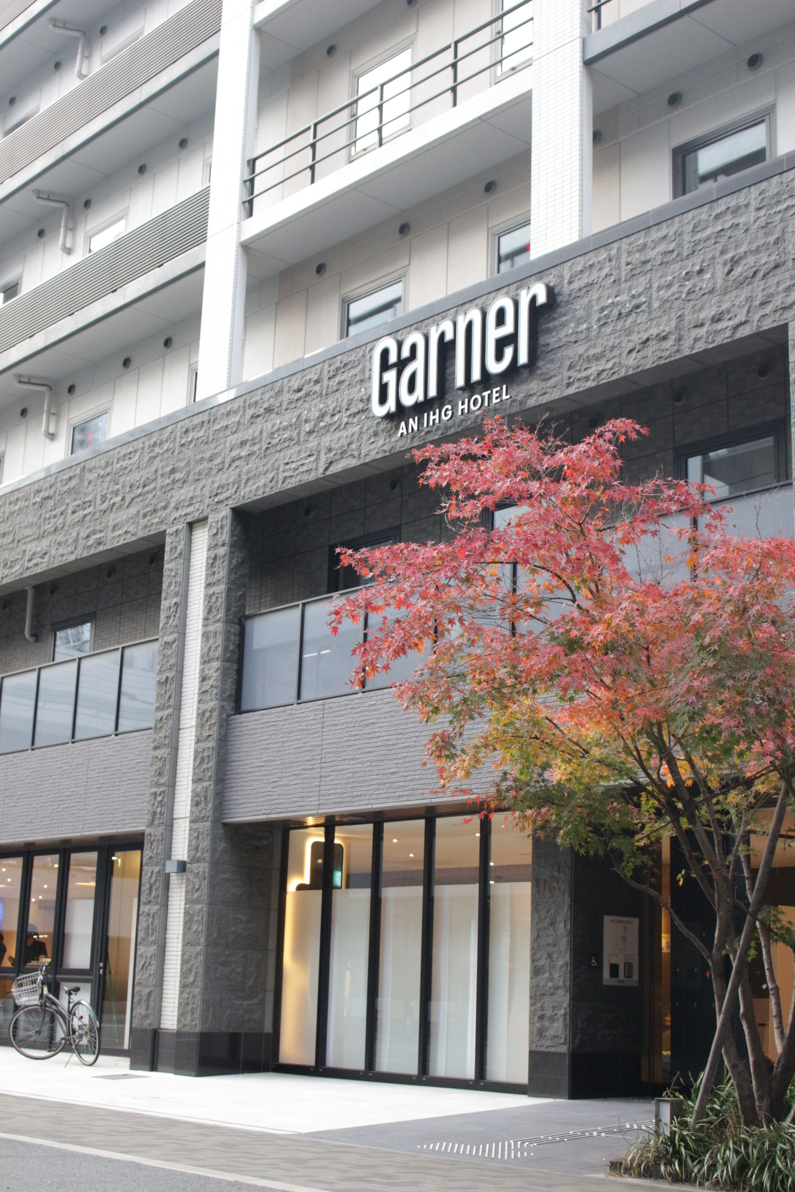 The exterior of the Garnier IHG Hotel with a modern architectural design, featuring a prominent sign and a bicycle parked outside.