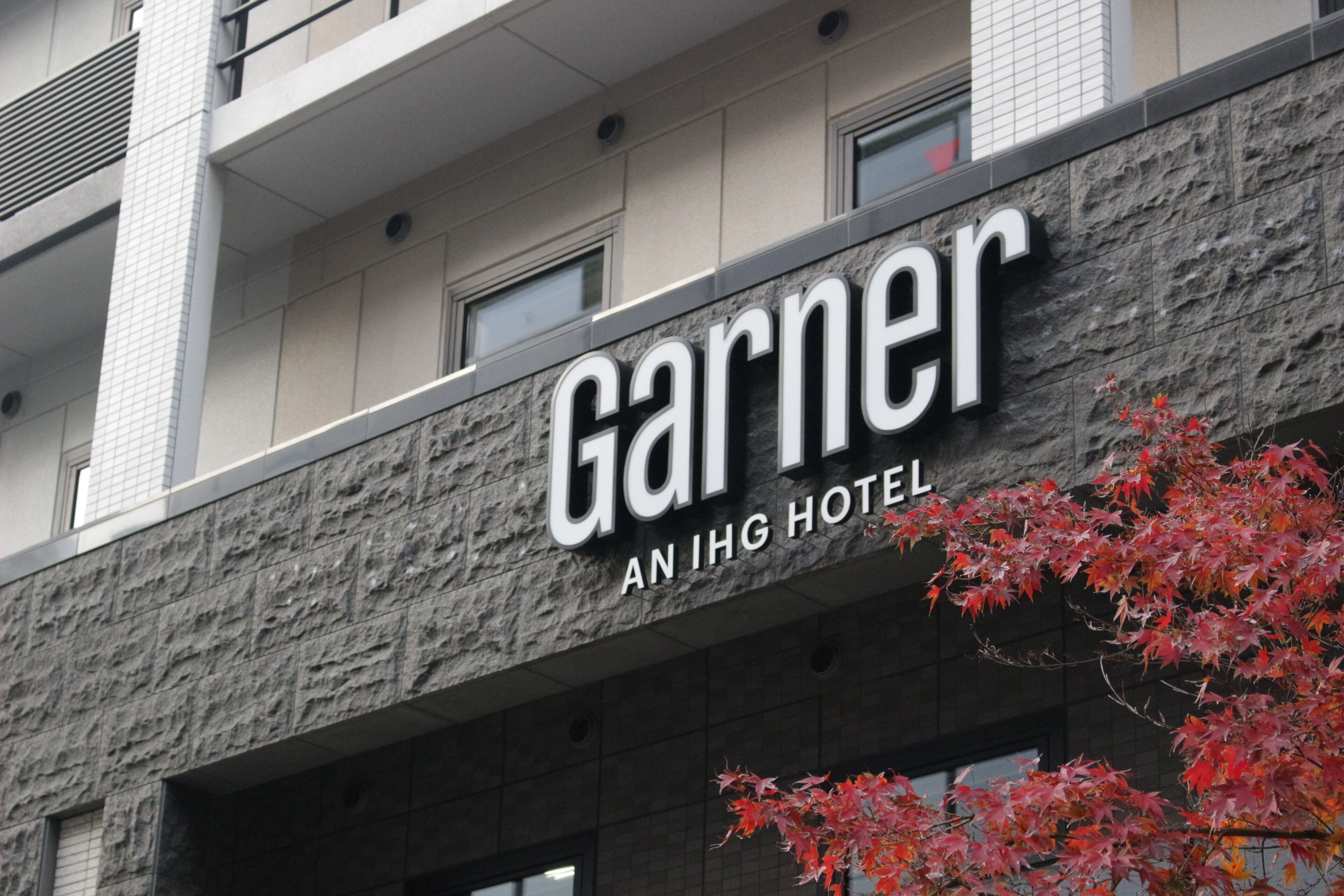 The exterior of the Garner hotel with a stone facade and a sign indicating it is an IHG hotel.