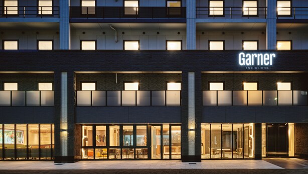 Un hotel con fachada moderna, amplios ventanales de vidrio y un cartel llamativo que dice