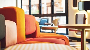 Un interior moderno con un sofá y una mesa redonda, ventanas amplias y vistas a edificios.