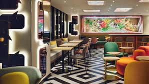Un interior moderno con suelo de estampado geométrico, diversas opciones de asientos, incluidas mesas y sillas, y una obra de arte grande colgada en la pared.