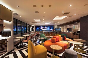 A modern interior with seating, a bar area, and a television screen. - Garner Osaka Honmachi Station by IHG (Osaka)