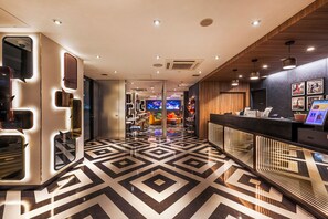 A hotel lobby with a geometric patterned floor, a reception desk, and a seating area with colorful chairs. - Garner Osaka Honmachi Station by IHG (Osaka)