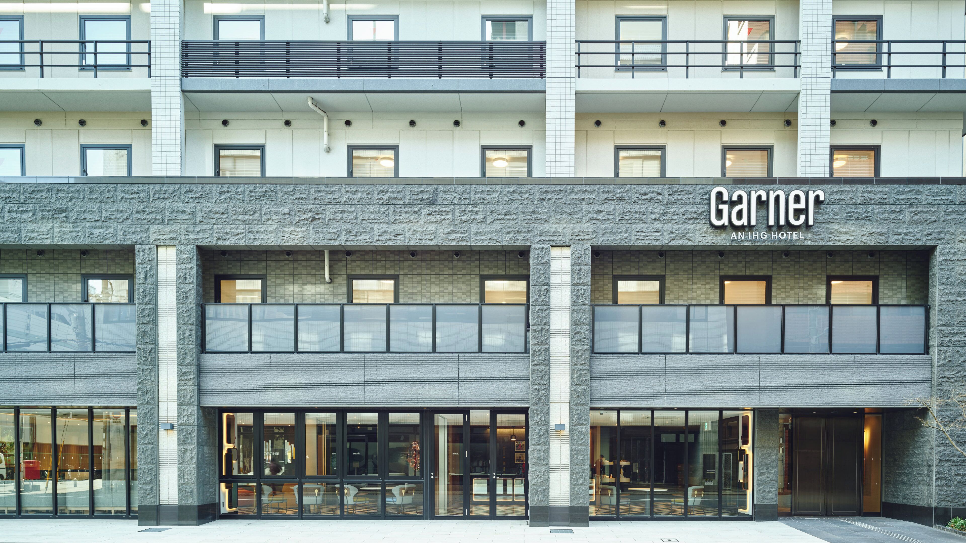 Een hotel met een moderne gevel, grote ramen en een buitengevel met een stenen textuur.