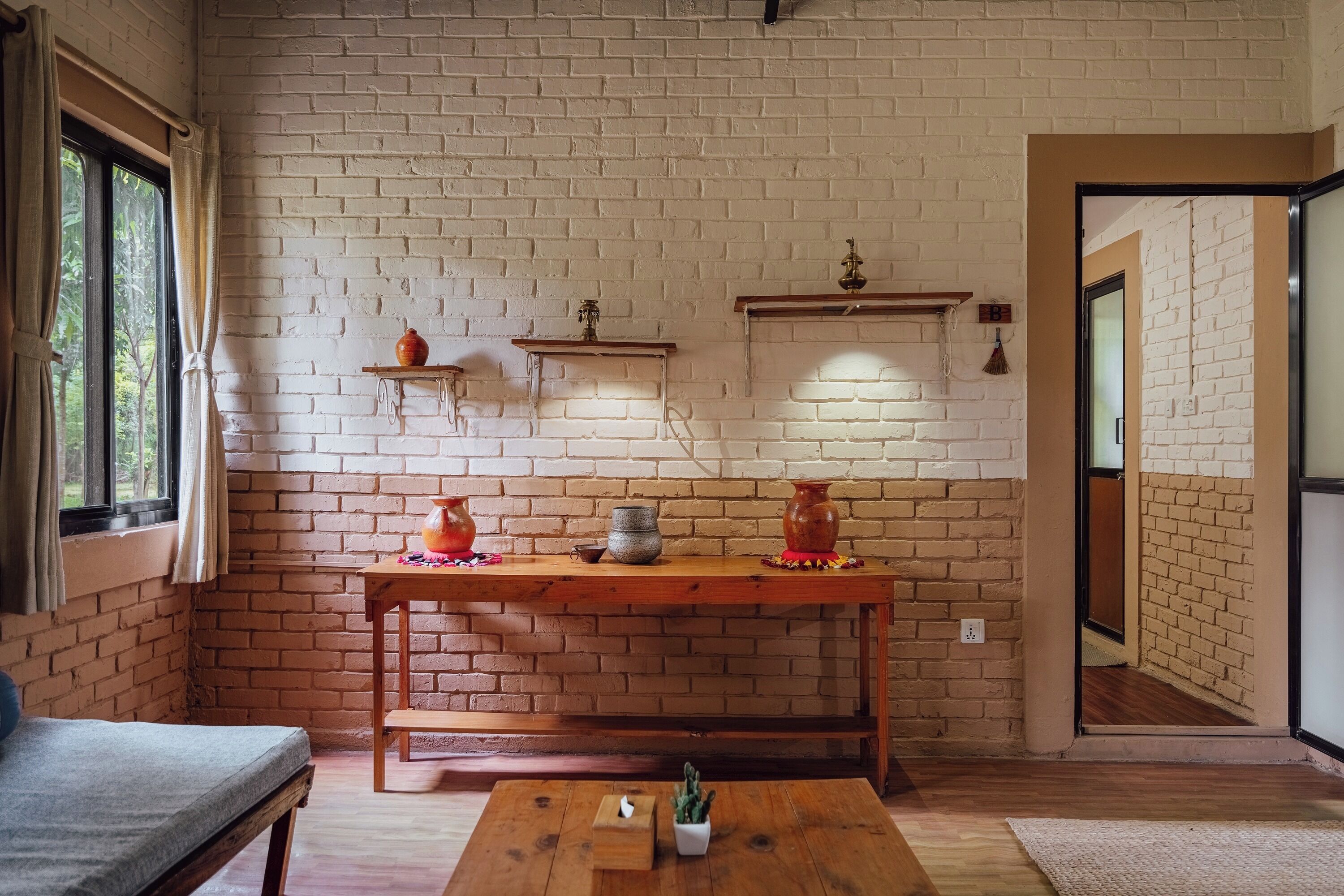 Ein Zimmer mit Backsteinwand, Holzmöbeln und einem Fenster mit Vorhängen.