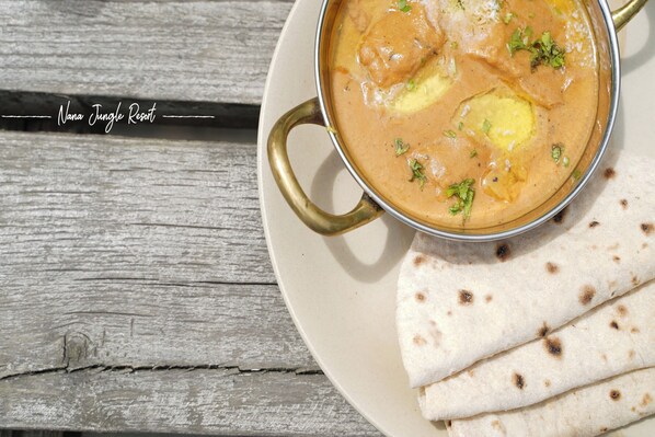 A bowl of curry with naan bread on a plate.