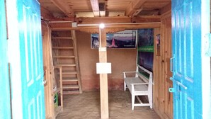 A room with a wooden ceiling, a staircase, a bed, and a poster on the wall. - Mount Mahabharat Homestay (Dhunkharka)