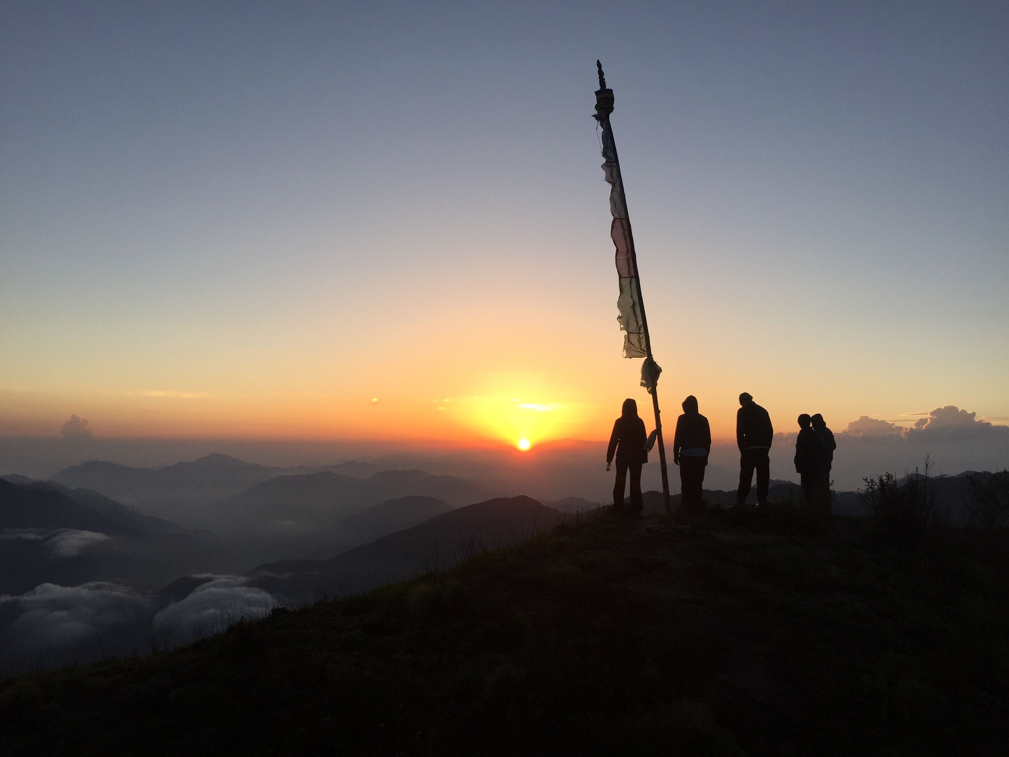 A group of people standing on a mountain ridge at sunset.