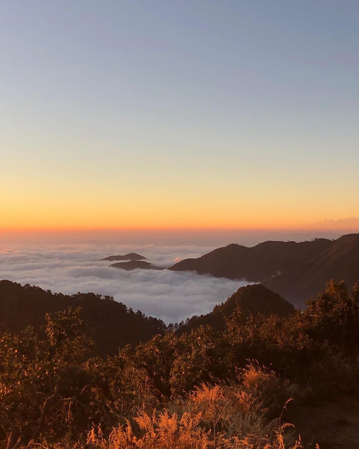 A mountainous landscape with a view of the horizon at sunset.