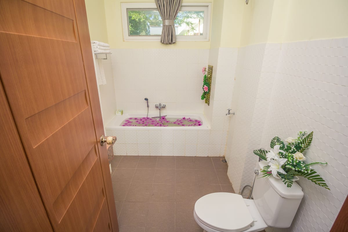 A bathroom with a bathtub, toilet, and a window with curtains.