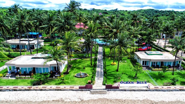 A resort with multiple buildings, palm trees, and a clear pathway leading to the entrance. - Ocean Blue Ngwe Saung Beach Hotel (Ngwe Saung)