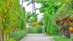 A pathway flanked by lush greenery and palm trees, leading to a building. - Ocean Blue Ngwe Saung Beach Hotel (Ngwe Saung)