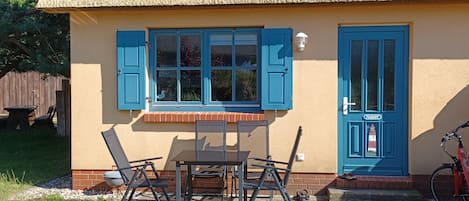 A building with a thatched roof, a blue door, and a table with chairs outside.